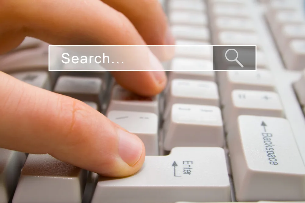A person's hand using a keyboard with a search box representing search generative experience